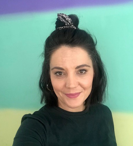 A woman with short, dark brown hair smiles at the camera in a selfie.