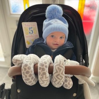 A baby in a pram with a sign