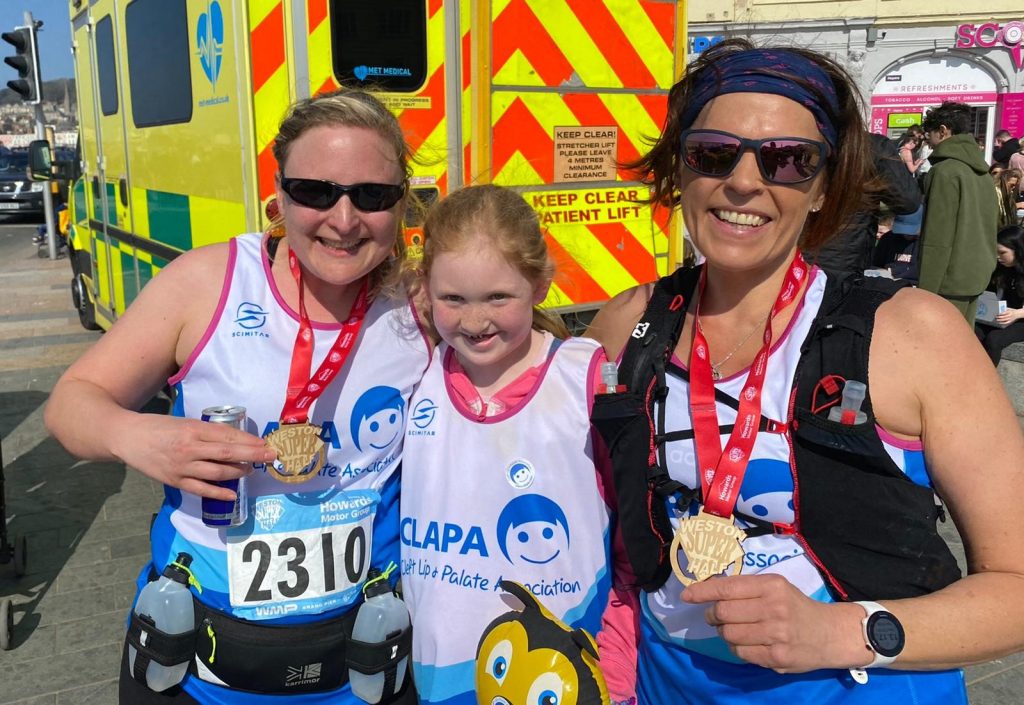 Two women and a girl wearing CLAPA running vests and medals