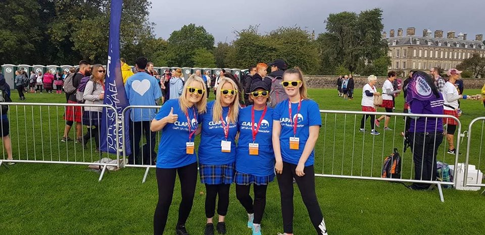 Four female fundraisers wearing blue CLAPA tops in a green park