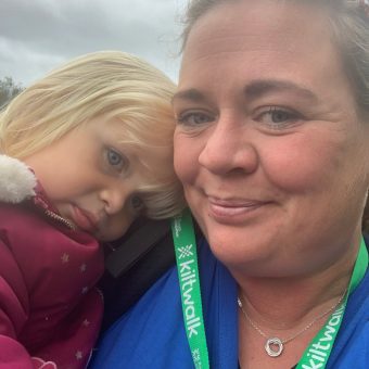 Woman in blue top holding a girl wearing a red coat