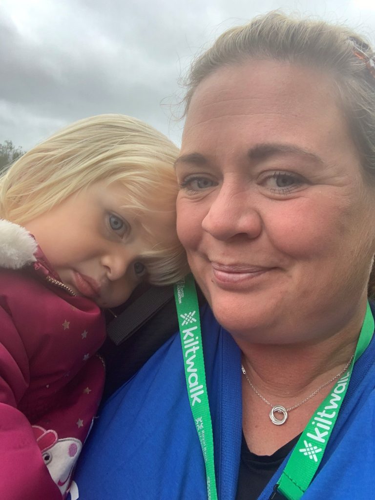 Woman in blue top holding a girl wearing a red coat