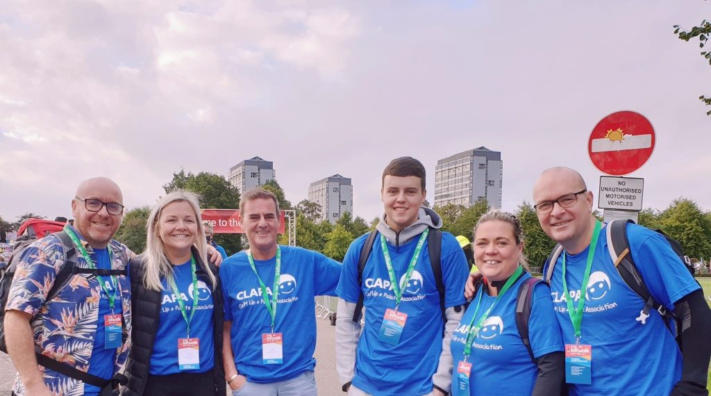 A group of fundraisers wearing blue CLAPA tops against a city skyline