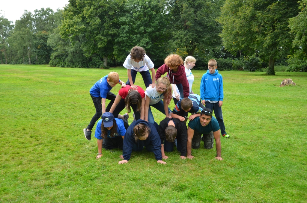 Young people in a human pyramid on grass