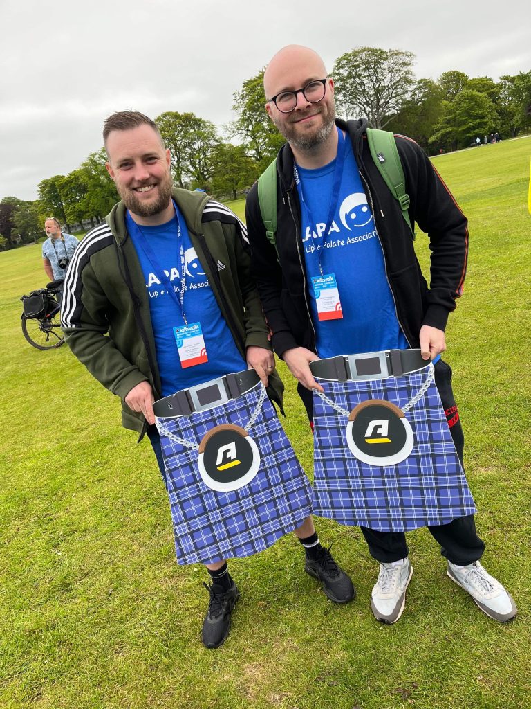 Two men in CLAPA Tshirts holding kilts