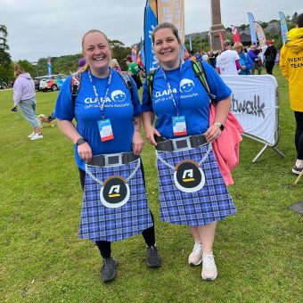 Two women in CLAPA Tshirts holding kilts