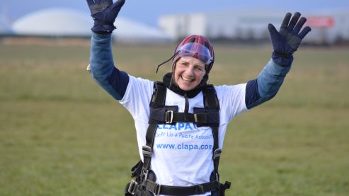 A person standing in an airfiled after a skydive