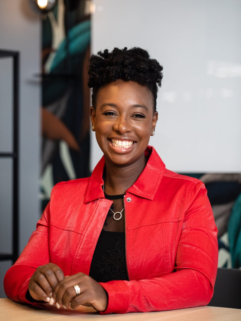 A photo of YolanDa Brown wearing a red jacket and smiling at the camera