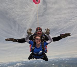 Woman tandem skydiving in blue t-shirt for CLAPA charity.