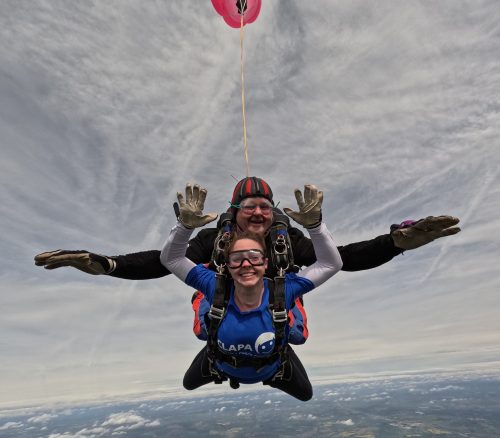 Woman tandem skydiving in blue t-shirt for CLAPA charity.